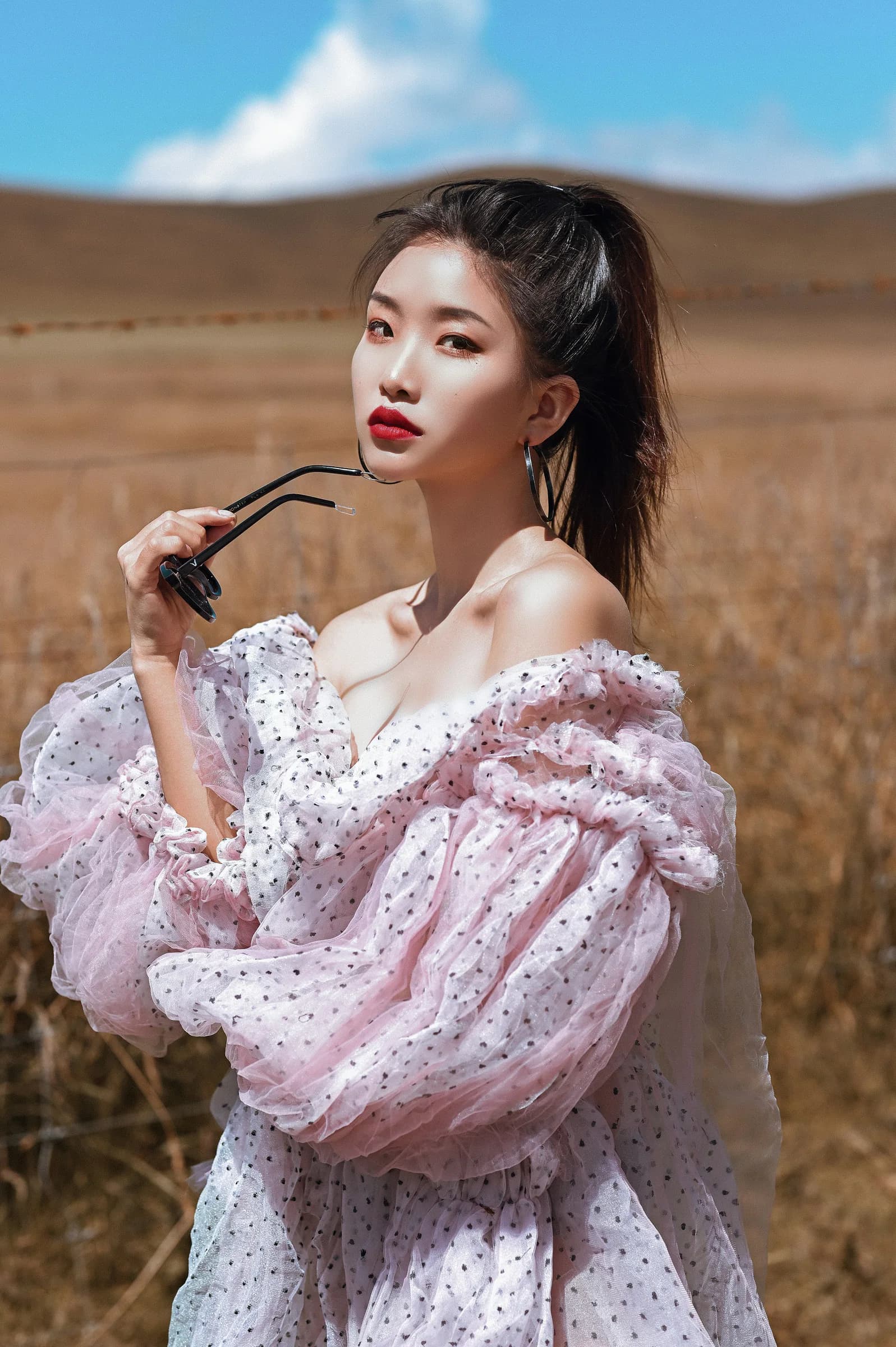 Woman in a pink ruffled dress standing in a golden field