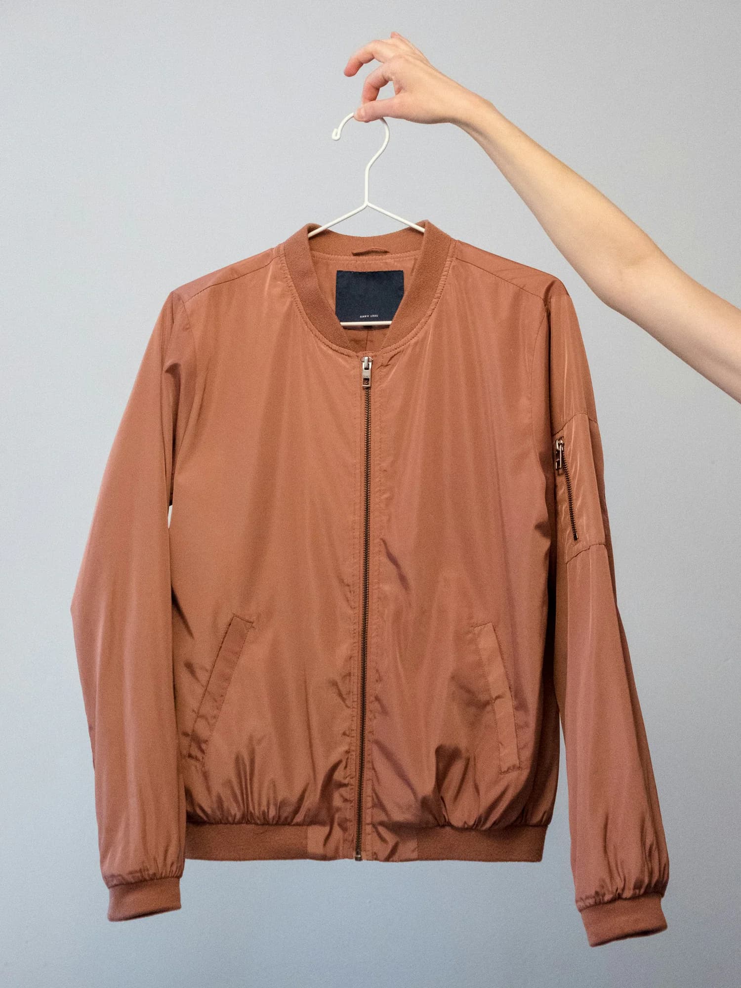 Rust coloured bomber jacket on a hanger