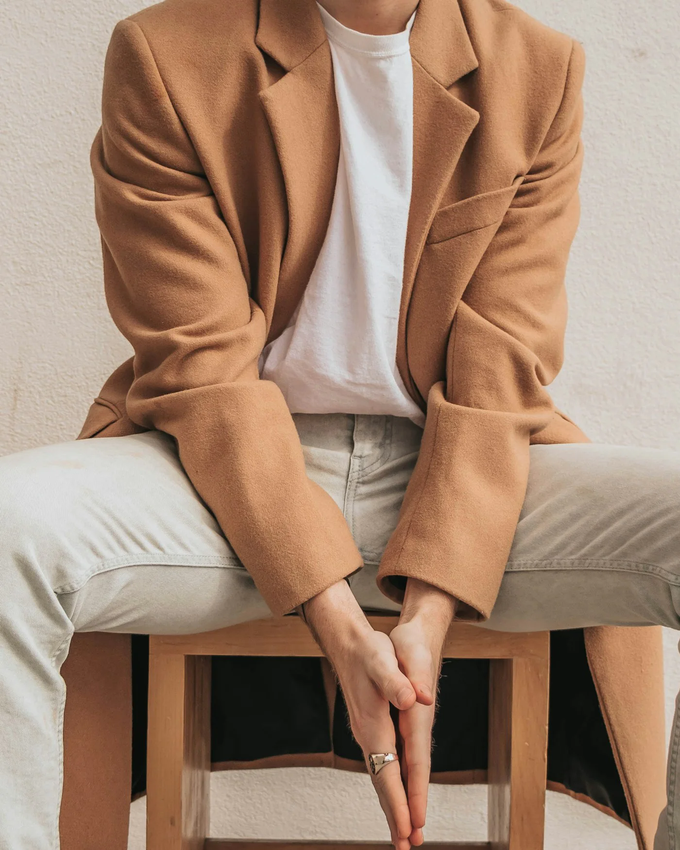 Man in a camel blazer sitting on a stool — detail