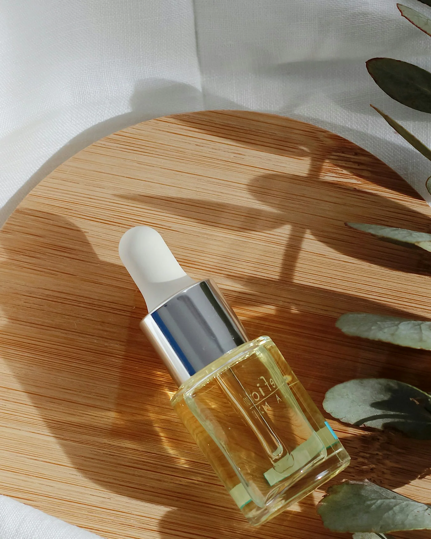 Amber dropper bottle of face oil with green leaves — detail