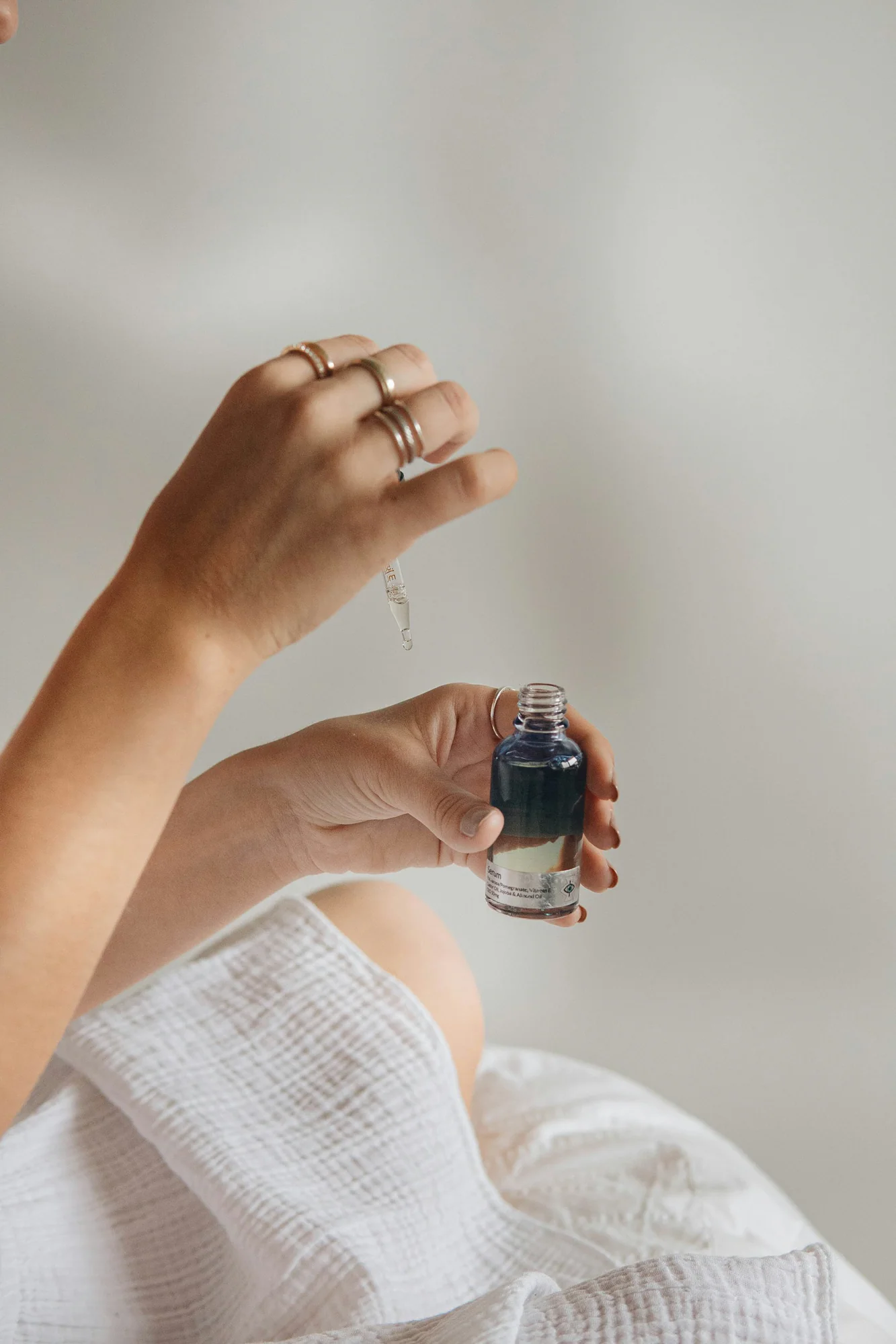 Hand holding a small dark glass serum bottle with a dropper
