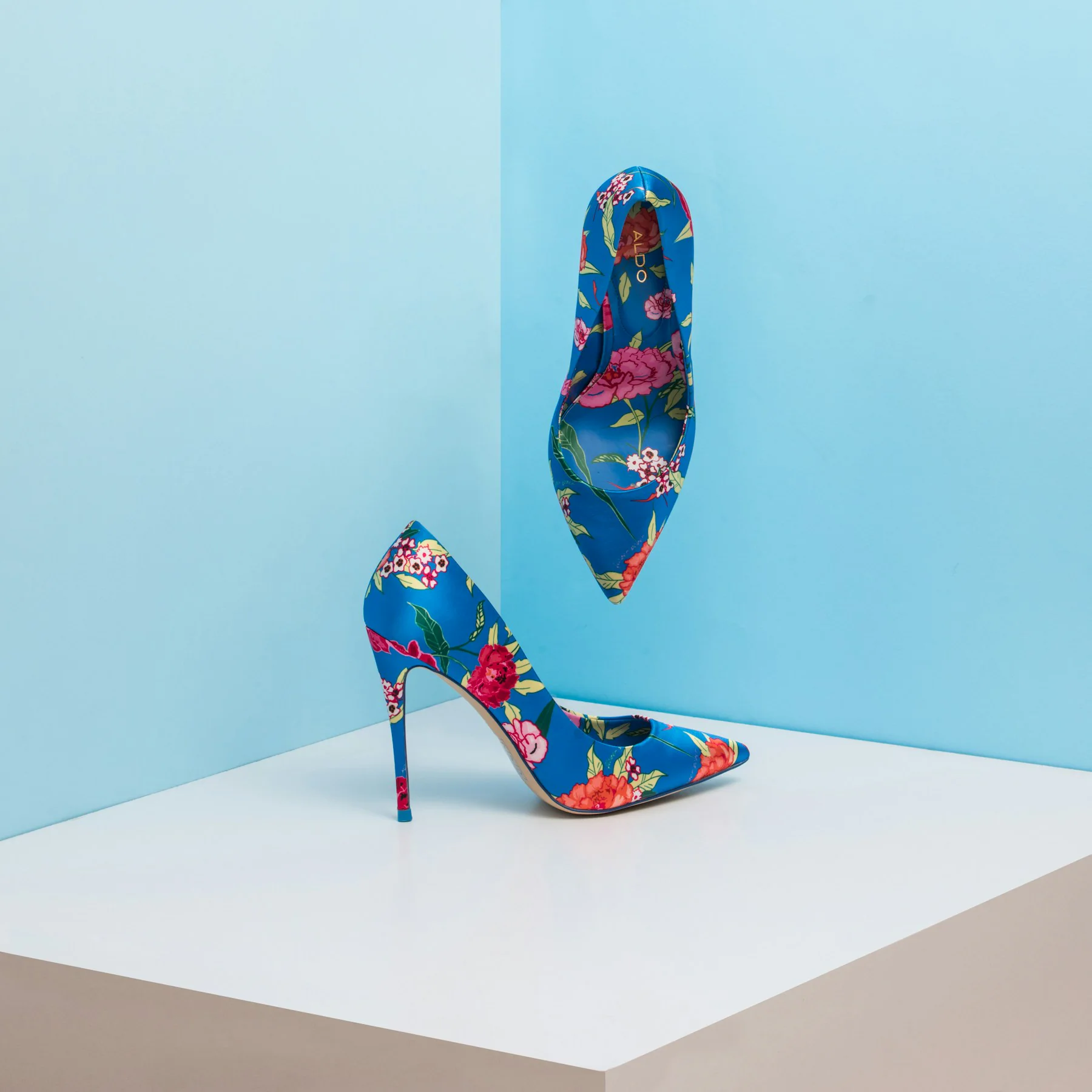 Pair of floral print stiletto heels against a blue background