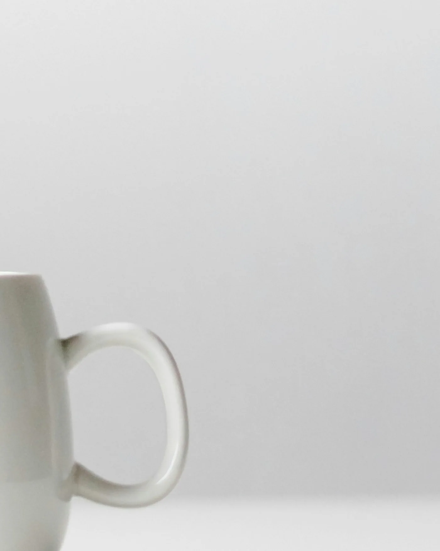 Plain white porcelain mug on a white surface — detail