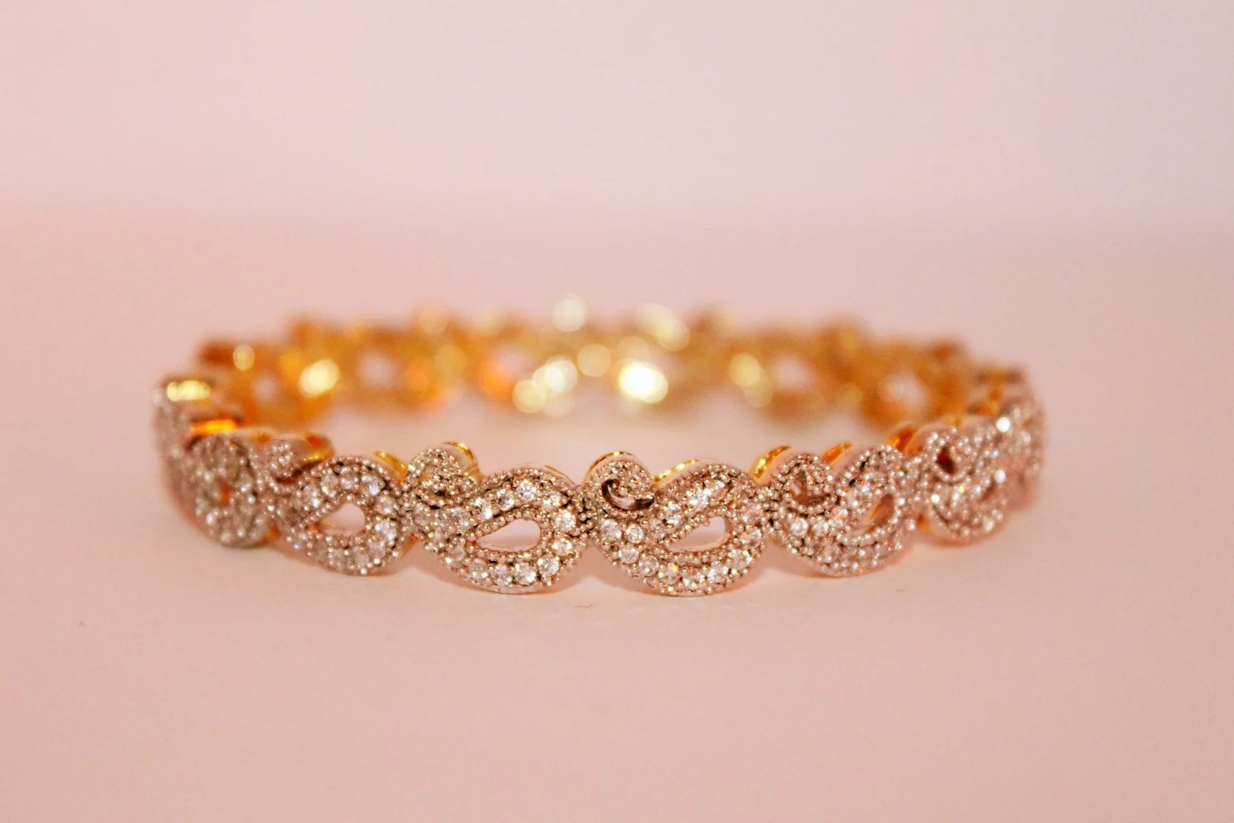Rose gold pavé bangle on a pink background